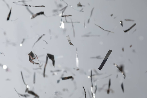 Shiny silver confetti falling down on light grey background - Fotoğraf, Görsel