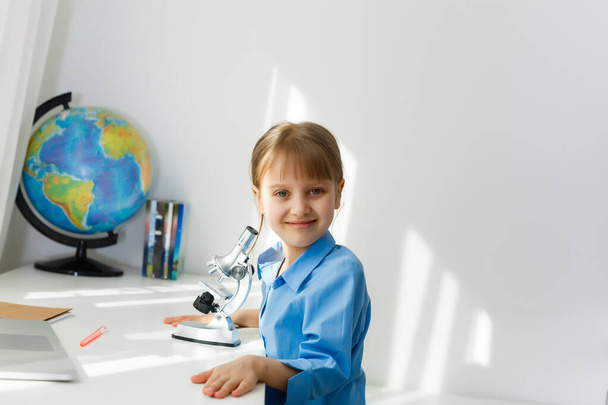 Etäopetus. Lapsi hymyilee iloisesti ja saa tietoa etänä. Pieni tyttö opiskelee verkossa oppimista kotoa. Online koulu. - Valokuva, kuva