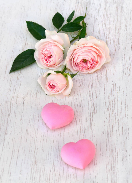 Blumen rosa Rosen mit rosa Herzen auf dem Hintergrund der weiß bemalten Holztisch mit Platz für Text. Dekoration zum Valentinstag - Foto, Bild
