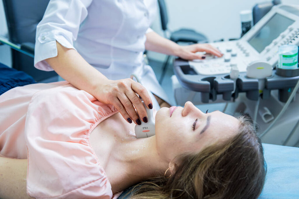 Doctor using ultrasound scanning machine for examining a thyroid of woman - Фото, зображення