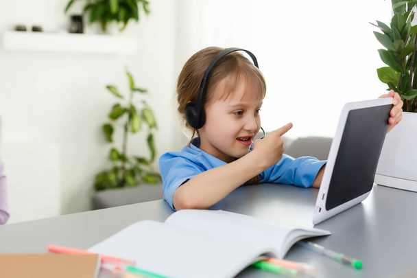 Remote lessons. The child smiles happily and gets knowledge remotely. Little girl study online learning from home. Online school. - Photo, Image