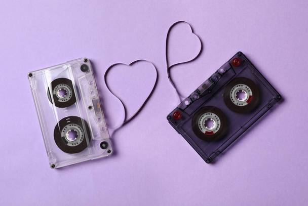 Music cassettes and hearts made of tape on violet background, flat lay. Listening love songs - Фото, зображення