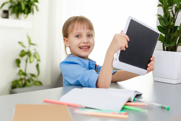 Fernunterricht. Das Kind lächelt glücklich und bekommt Wissen aus der Ferne. Kleine Mädchen lernen online von zu Hause aus. Online-Schule. - Foto, Bild