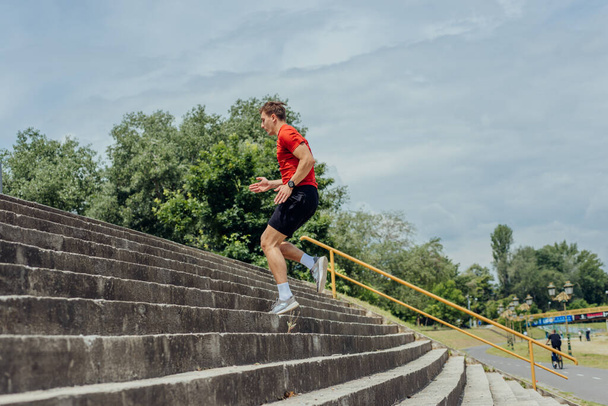 Giovane atleta maschio attraente che esercita e corre sulle scale nel parco. - Foto, immagini