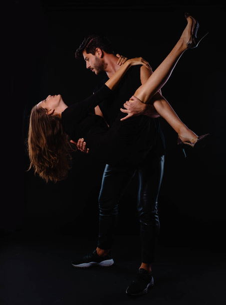 Attractive young man and woman posing against a black background - Photo, Image