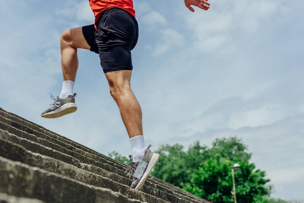 Fit male athlete performing stairs workout, running up climbing stairs performing outdoor track cardio. - Photo, Image