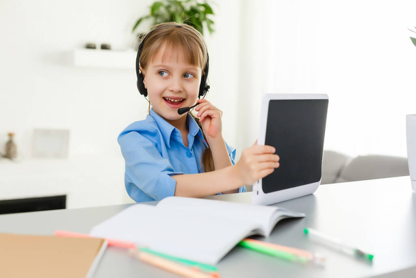 Remote lessons. The child smiles happily and gets knowledge remotely. Little girl study online learning from home. Online school. - Фото, зображення