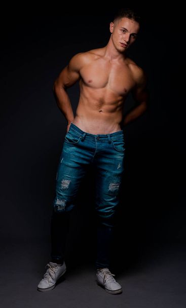 Stilvoller junger Mann in blauer Jeanshose posiert halb nackt - Foto, Bild