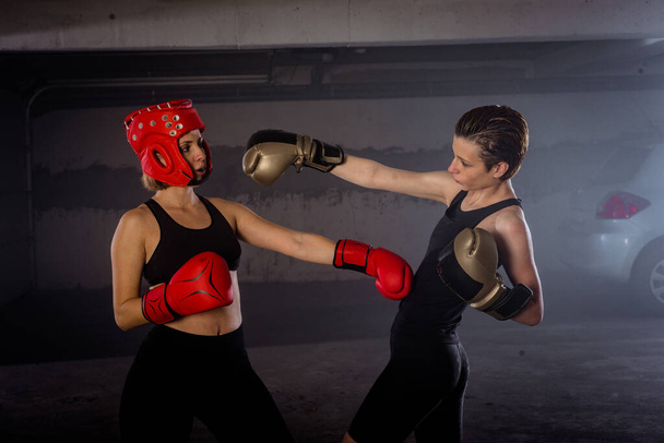 Дві професійні жінки-боксери б'ються в агресивному бою в гаражі
 - Фото, зображення