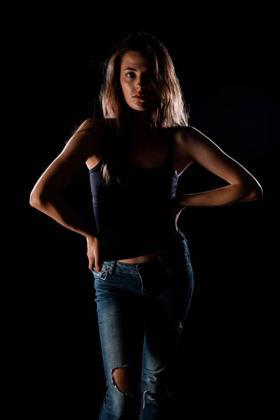 Portret pięknej stylowej dziewczyny ubranej w czarny top i podarte dżinsy - Zdjęcie, obraz