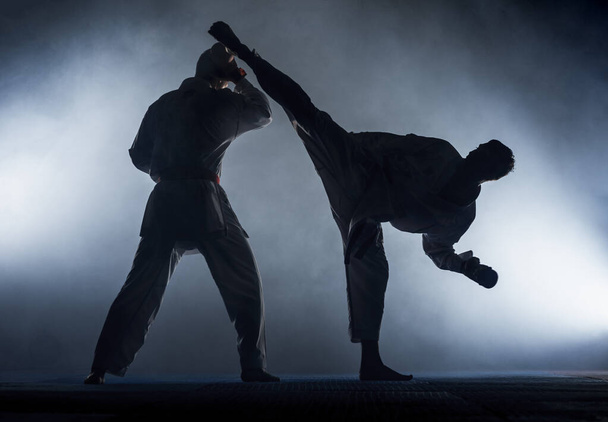 Mladý muž cvičí karate pohyby, bílé kimono a červený pás - Fotografie, Obrázek