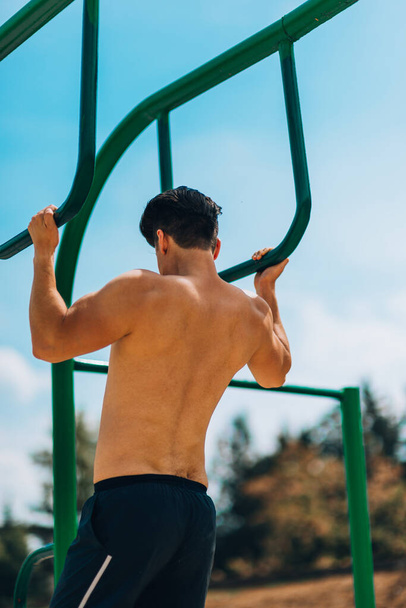 Crossfit férfi gyakorló push up edzés újra kék ég fém rúd - Fotó, kép