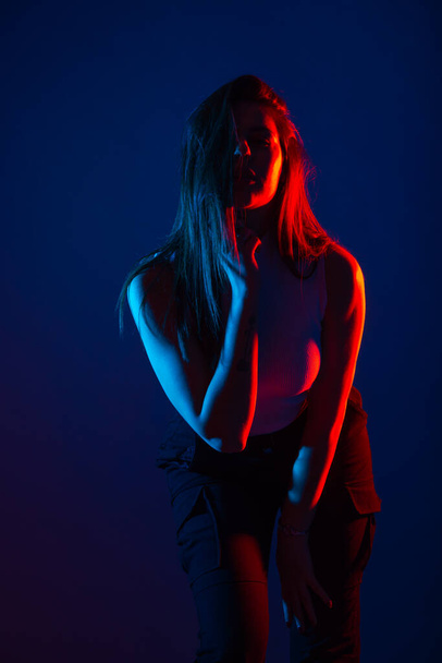 Female model posing in studio with red and blue colors at high contrast. - Foto, imagen