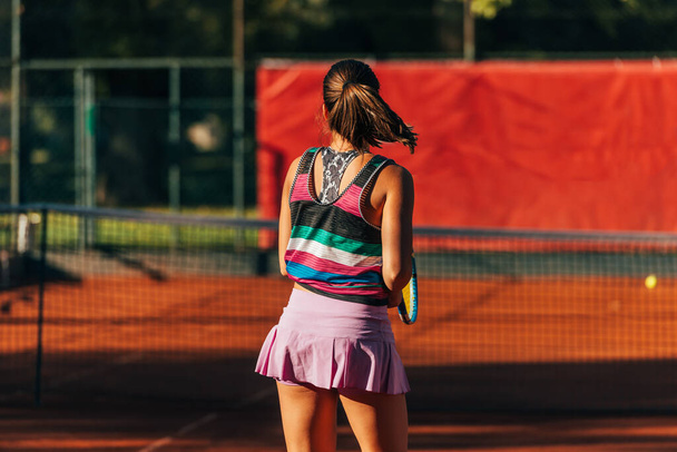 Vista dal retro di una giovane donna che paga il tennis su un campo fuori - Foto, immagini