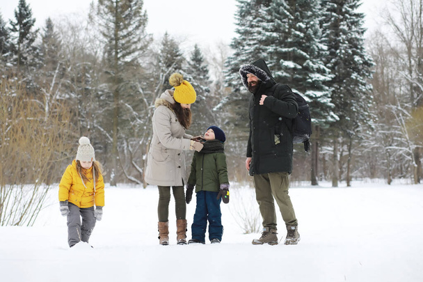 Щаслива сім'я грає і сміється взимку на свіжому повітрі в снігу. Міський парк зимовий день
. - Фото, зображення