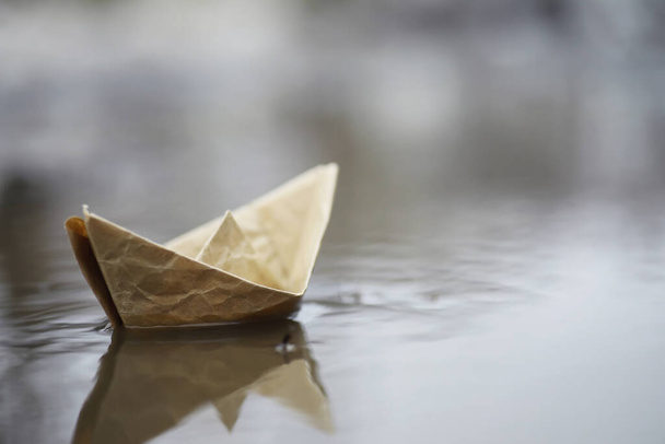 通りの水の中に紙のボート。コンセプトは早春。雪解け水と波に乗る折り紙の舟. - 写真・画像
