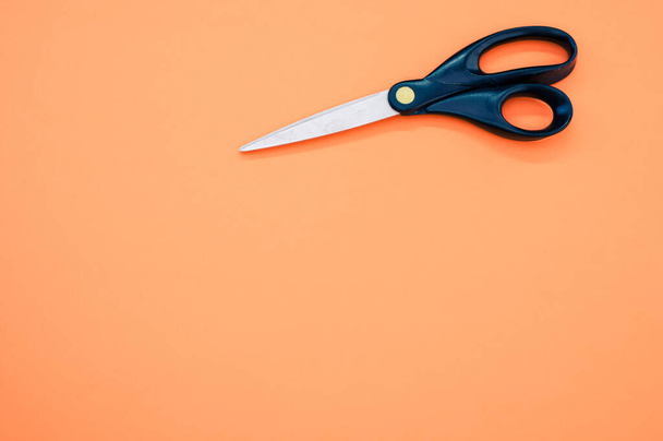 Black scissors isolated on an orange background - Φωτογραφία, εικόνα