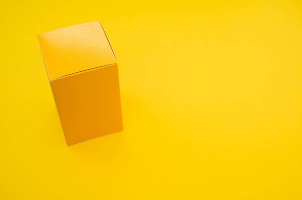 A yellow paper cube isolated on a yellow background - Foto, afbeelding