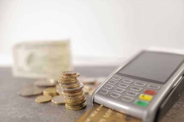 A closeup shot of coins and a pos terminal on the table - 写真・画像