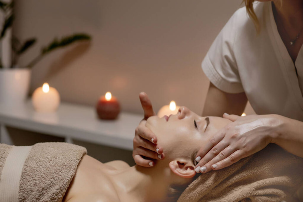 Relaxing massage. Woman receiving head massage at spa salon, side view. - Фото, изображение