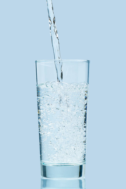 Pouring water. Pouring fresh clean drinking water to glass. - Foto, Imagen