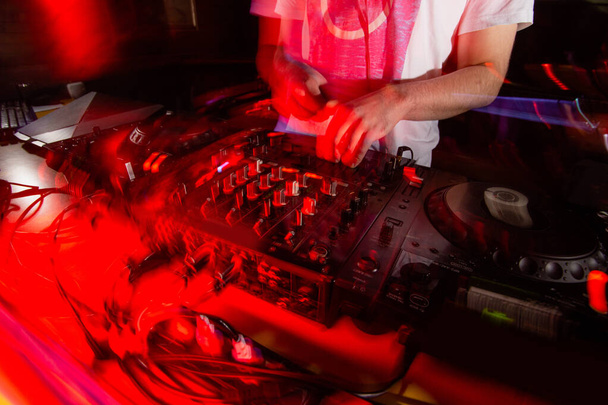 Spüren Sie die Musik Cut Schuss von DJ bleiben in der Nähe verschwommenen Konsole. Live-Set im Nachtclub. Irres Party-Konzept. Leuchtend rote Lichter im Vordergrund. Raven die ganze Nacht. - Foto, Bild