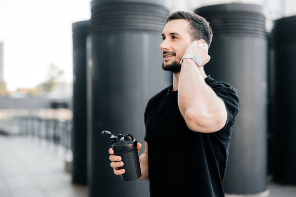 A sportoló szünetelteti az edzést, hogy válaszoljon a hívásra. Barátságos férfi beszél telefonon egy ügyféllel, miközben kocogás után pihen. Reggeli edzés a szabadban. - Fotó, kép