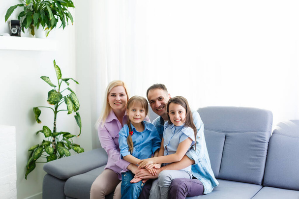 Cheerful young family with kids laughing sitting on couch together, parents with children enjoying entertaining at home - Photo, Image