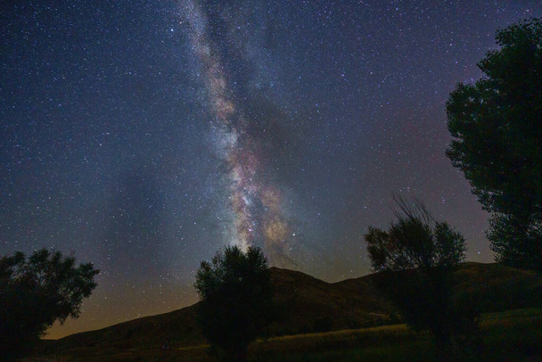 De donkere nachtelijke hemel met veel sterren boven een veld - Foto, afbeelding