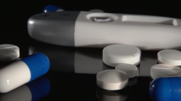 Thermometer, tabletten en capsules close-up op een zwarte achtergrond. - Video