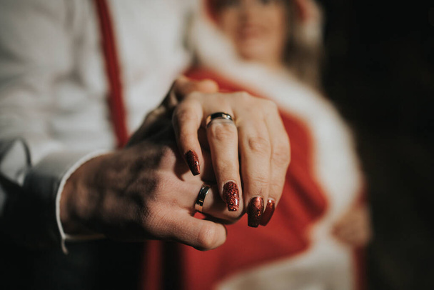 A selective focus shot of the groom's and bride's hands wearing the wedding rings - Fotó, kép
