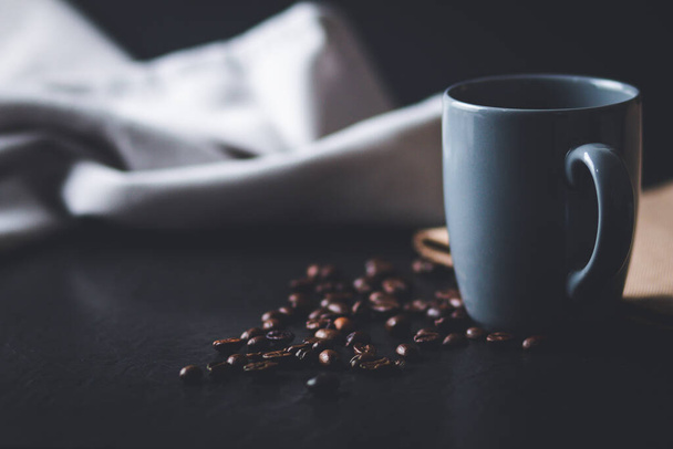 A selective focus shot of burlap and a cup of hot coffee surrounded with beans - Zdjęcie, obraz