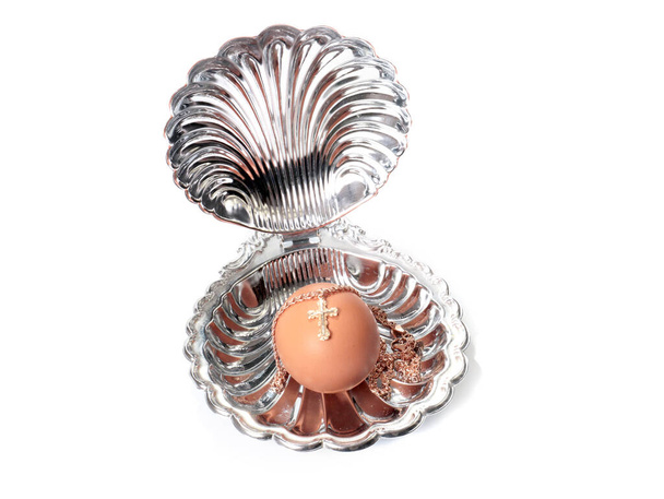 an Easter egg decorated with a golden cross lies in a decorative shell - Φωτογραφία, εικόνα