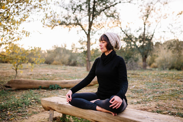 Vrouw die yoga beoefent en mediteert op de bank van het park - Foto, afbeelding