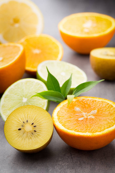 Mixed citrus fruit lemons, orange, kiwi, limes on a gray background.  - Fotó, kép