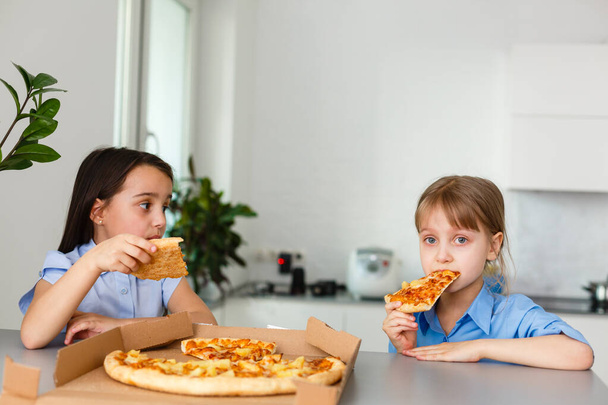 Due bambini felici che mangiano fette di pizza. - Foto, immagini