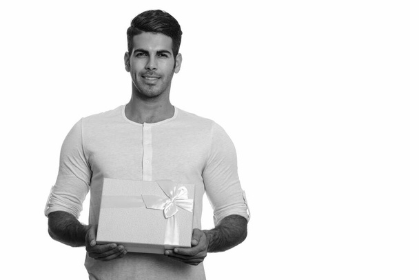 Joven hombre persa feliz sonriendo y sosteniendo caja de regalo - Foto, imagen