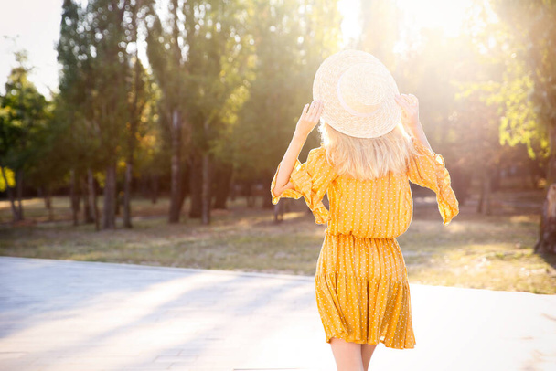 Woman in stylish yellow dress and straw hat outdoors, back view - Foto, Bild