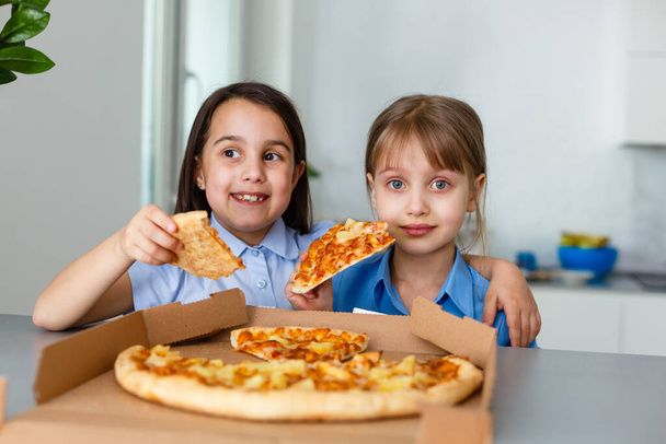 Two happy little child girl friends eating pizza slices. - Foto, imagen
