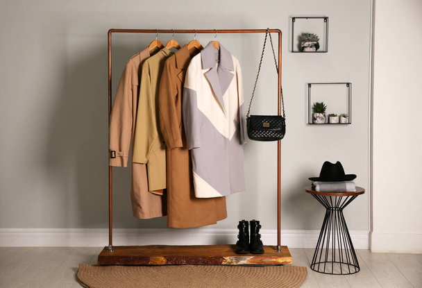 Different warm coats on rack in stylish room interior - Foto, Imagen