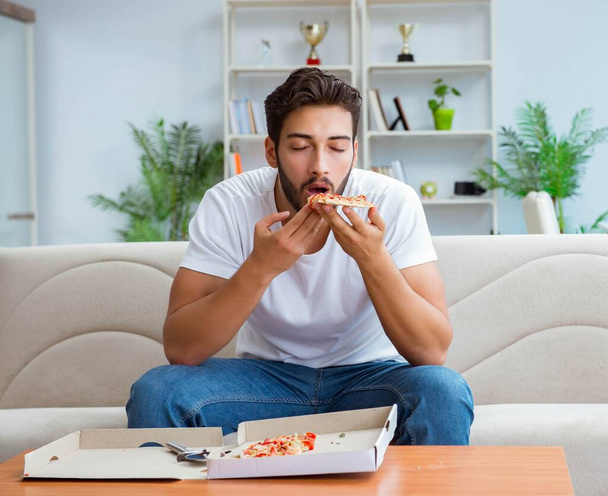 Hombre comiendo pizza teniendo una comida para llevar en casa descansando relajado - Foto, Imagen