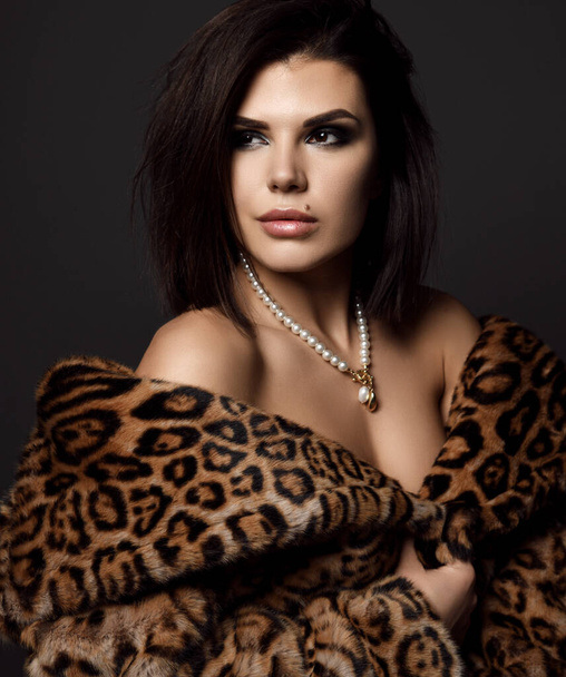 Portrait of young pretty sexy brunette woman model in leopard fur coat with naked shoulders looking aside - Foto, afbeelding