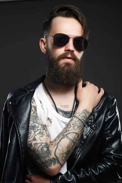 fashionable handsome man in sunglasses. Brutal bearded Sexy boy in leather coat - Photo, Image