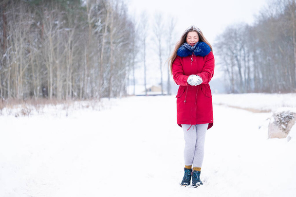 Young woman in red coat walk on winter road - Фото, изображение