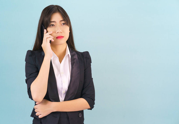 Young Asian women in suit standing posing using her phone against blue background - Photo, image