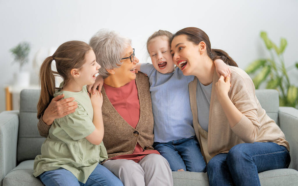 A nice girls, their mother and grandmother are hugging and  enjoying spending time together at home.  - Valokuva, kuva