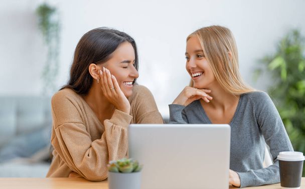 Two happy young women using laptop. Friends spending time together. - Photo, image