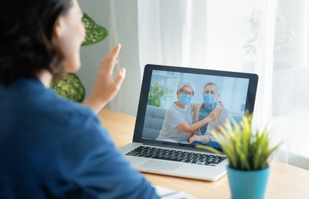 Senior couple wearing face masks and using pc for remote talking during coronavirus and flu outbreak. Virus and illness protection, home quarantine. COVID-2019. - Foto, Bild