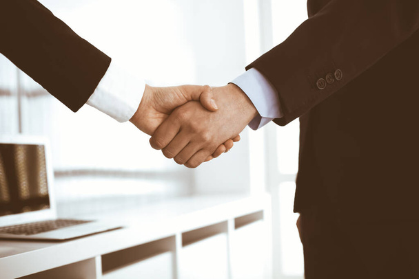 Businessman and woman shaking hands in office. Concept of handshake as success symbol in business - Foto, Imagem