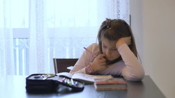 Młoda dziewczyna odrabia pracę domową podczas zamknięcia z powodu pandemii koronawirusowej - Materiał filmowy, wideo